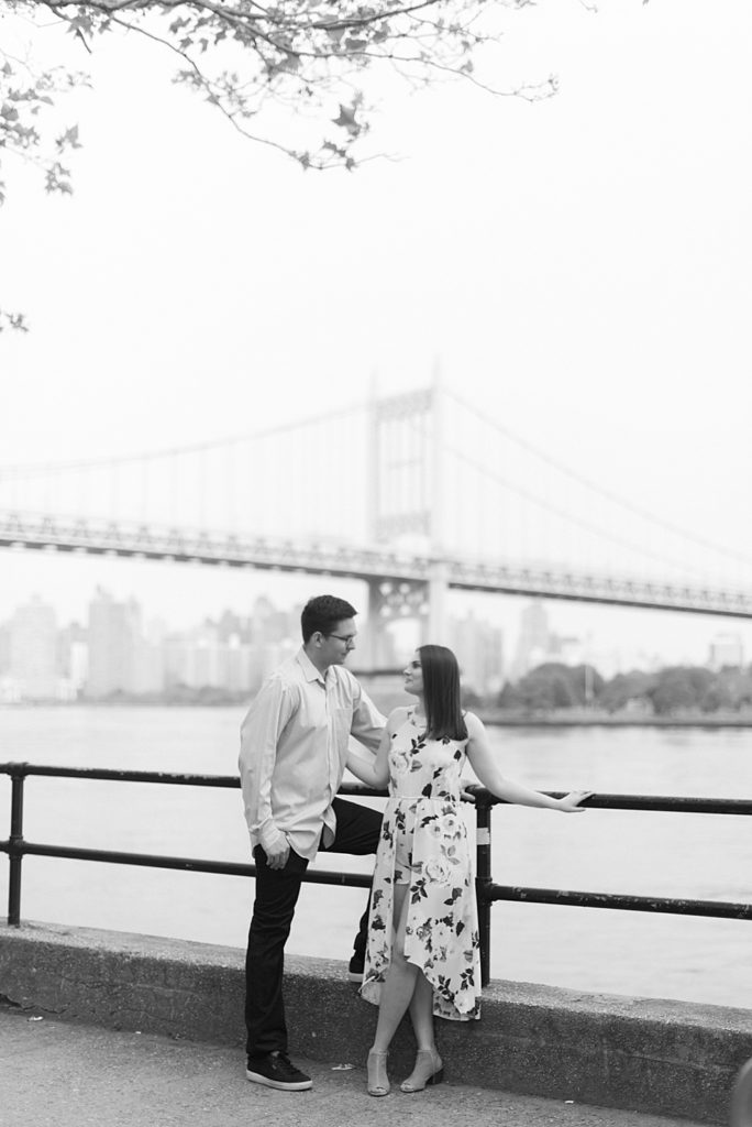 black and white engaged couple in front of NYC bridge