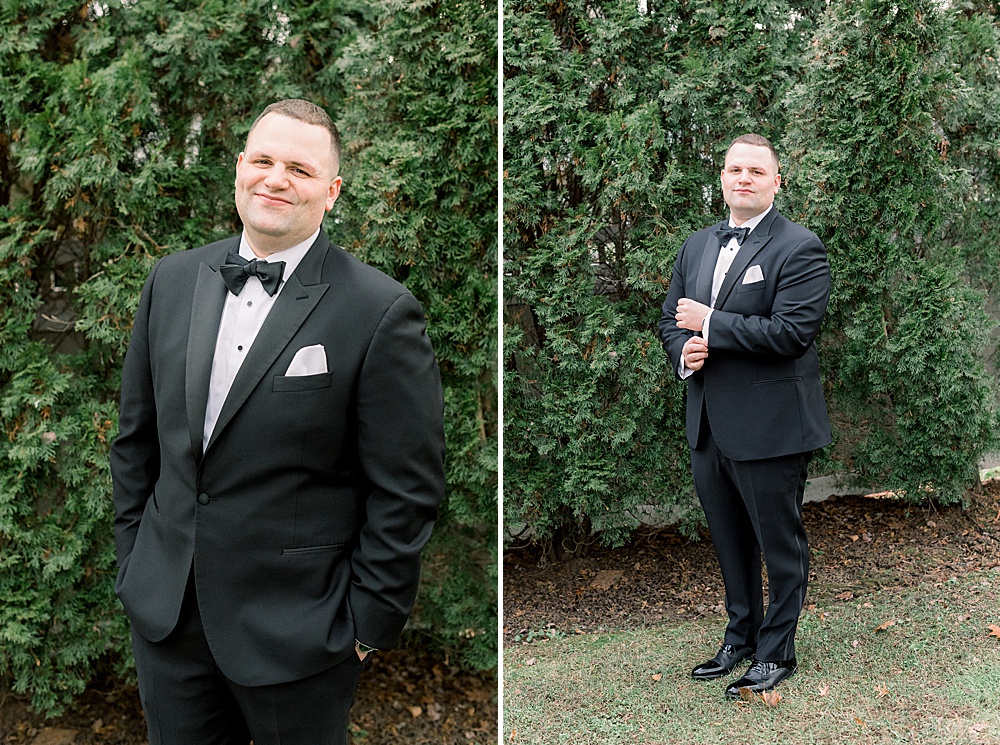 groom standing in front of greenery