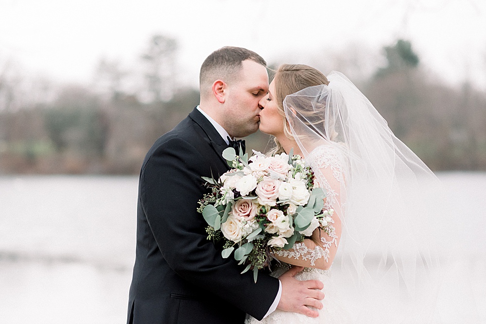 bride and groom kiss behind veil