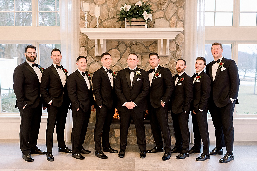 groomsmen in front of stone wall